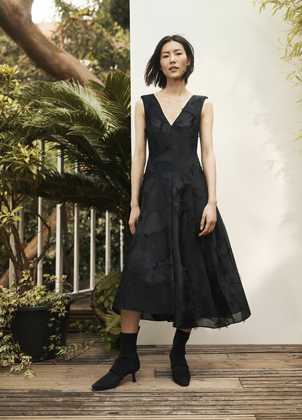 Svart klänning med djup v-ringning i återvunnen polyester och svarta stövletter med spetsig tå. H&M Conscious Exclusive-kollektionen för höst/vinter 2018