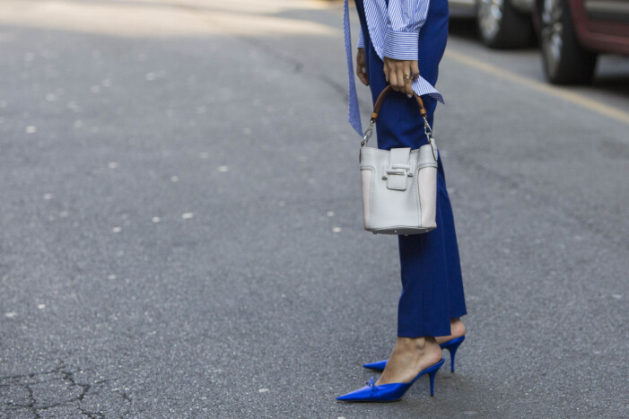 Klassiska pumps med spetsig tå och en enkel handväska toppar din look på bästa sätt! Foto: TT Närbild på en kvinna med blå byxor och blå pumps och en off-white skinnväska.