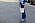 Närbild på en kvinna med blå byxor och blå pumps och en off-white skinnväska.