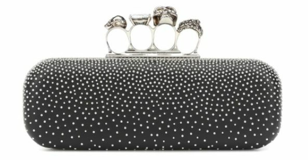 Clutch, Alexander McQueen/Mytheresa.com. <a target="_blank" rel="nofollow" href="https://apprl.com/al/6hp5/">Klicka på länken för att komma direkt till produkten!</a> Svart avlång clutch med fyra hål för fingrarna prydda med dödskallar och strass. Väskan är stel och prydd med massa små, runda silvriga nitar/prickar. Clutch från Alexander McQueen.