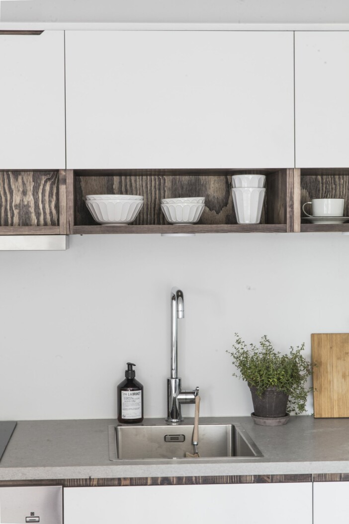 På de öppna hyllplanen: Vitt porslin från GAD, vita kaffekoppar, Månses design. Diskmedel från L:a Bruket. Diskborste från Iris Hantverk. Attefallshus Sommarnöje GAD Gotland köket hyllor