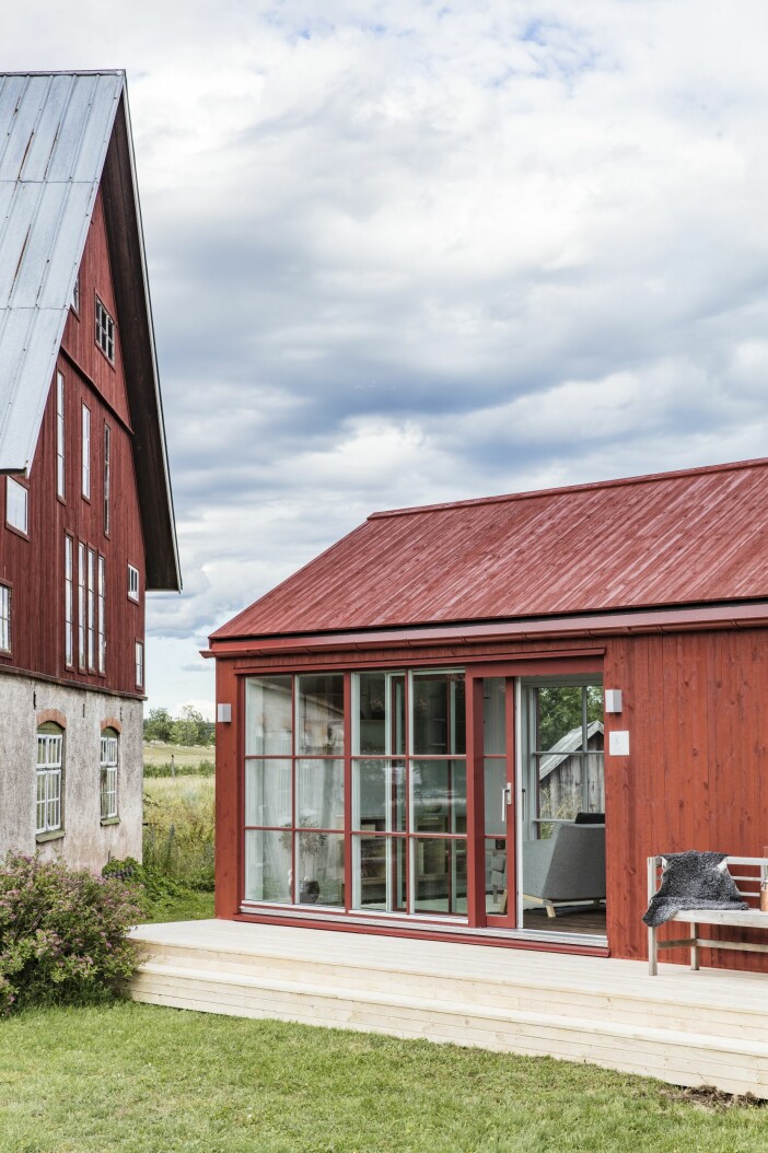 Attefallshuset från Sommarnöje är placerat i skydd av den gamla, vackra ladan på tomten på Gotland. Attefallshus Sommarnöje GAD Gotland trappa glasparti