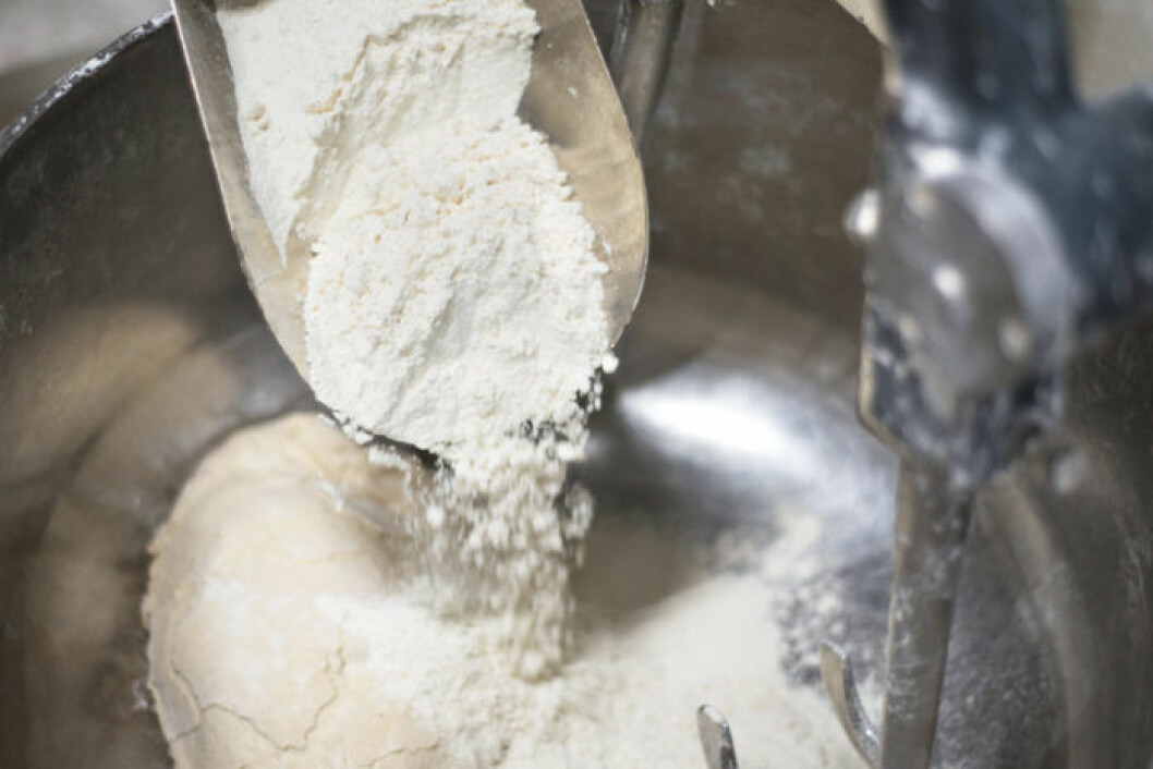 Tillsätt lite mjöl i taget. Bild: Shutterstock/IBL Mjöl hälls ner i bakmaskin.