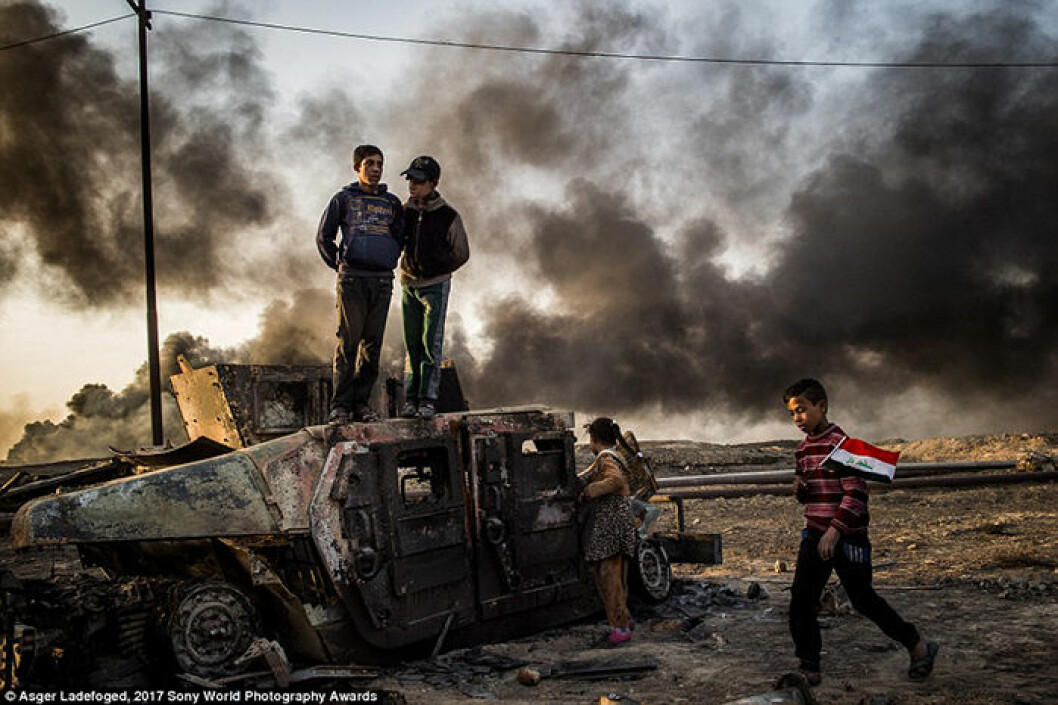 Taha Sirhan, 11, bär den irakiska flaggan över de brända oljefälten i Qayyarah, Irak. Hans pappa, som var polis, dödades av ISIS. Fotograf: Asger Ladefoged