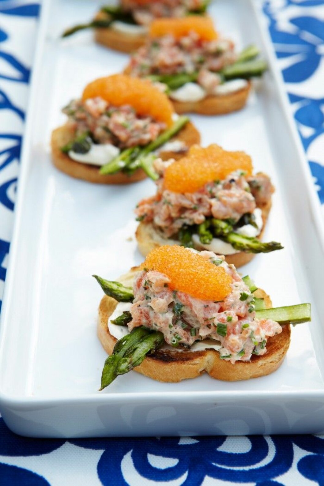 Bruschetta med laxtartar och sparris. Bruschetta med laxtartar och sparris på vitt fat