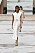 Modell med vit klänning i minimalistisk modell med hålmönster och blommönster på. Stylad med beigea accessoarer: brett bälte, mini clutch och skor. Look från Chloé.
