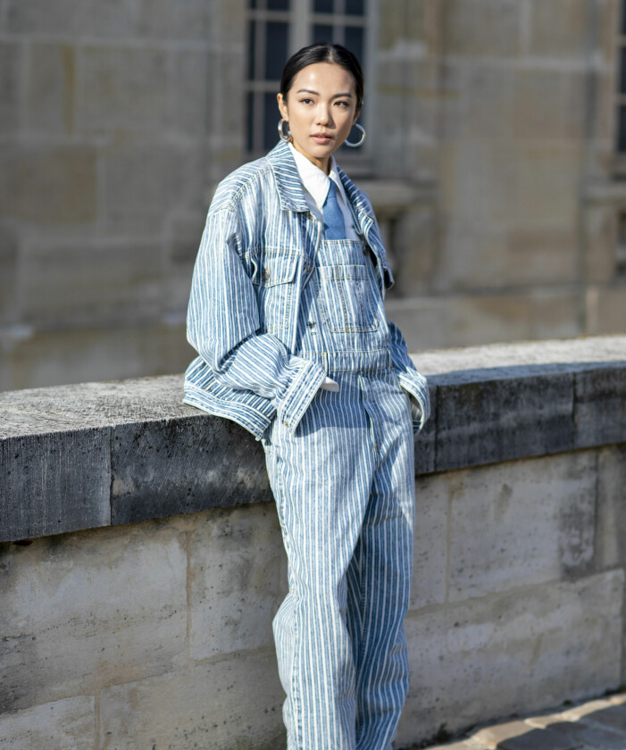 Hängselbyxor och jeansjacka i en mer avslappnad denimlook. Hängselbyxor i denim och matchande jeansjacka på gäst vid modeveckan i Paris.