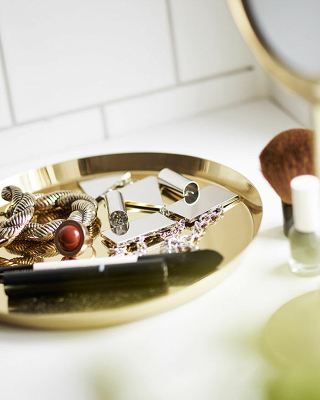 En bricka med dina favoritaccessoarer kan göra stor skillnad i badrummet. Foto: Vedum Bricka i mässing med smycken i badrummet