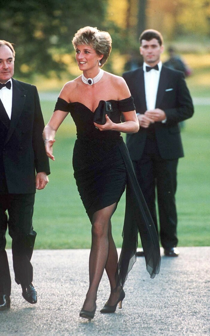 Samma dag som den här bilden togs pratade Prins Charles om sin relation med Camilla Parker-Bowles offentligt för första gången. Dianas svar på det hela var “The Revenge dress”... Prinsessan Diana i en svart miniklänning med bara axlar och ett brett pärlhalsband. I handen har hon en svart kuvertväskan och svarta pumps på fötterna.