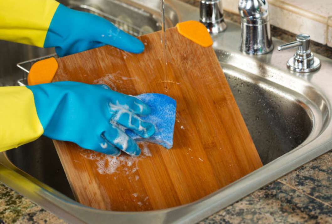 Kom ihåg att salt också är bra för att ta bort dålig lukt. Bild: Shutterstock/IBL Kvinna med diskhandskar diskar skärbräda i trä med disksvamp.