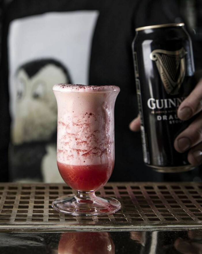 Rosa drink med skum, och en burk Guinness