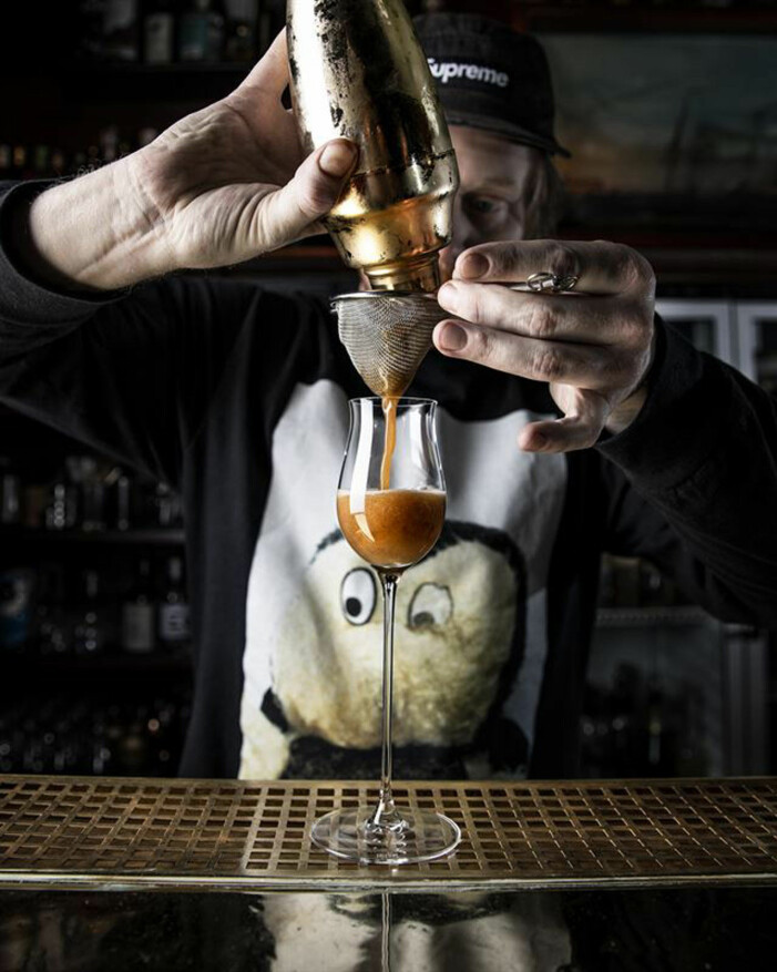 Man häller upp en brun drink i ett glas