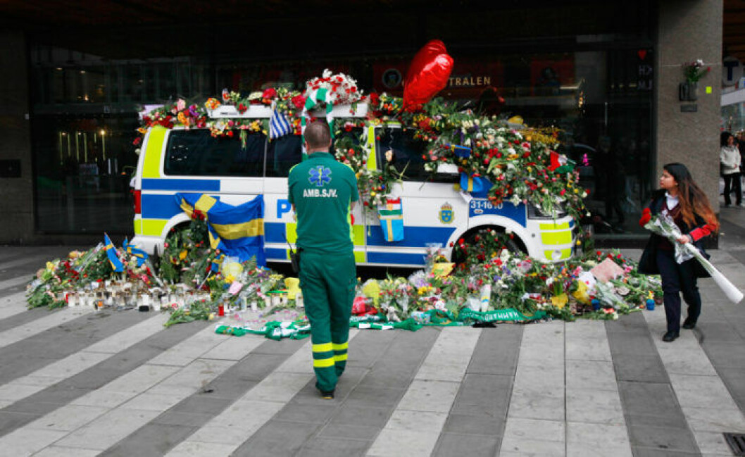 Bild: IBL Bildbyrå Drottninggatan i Stockholm april 2017. En målad polisbil täckt med blommor. Framför står en ambulanssjukvårdare och tittar på polisbilen.