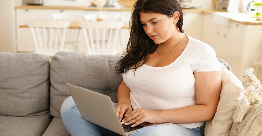 kvinna sitter i en soffa med en dator i knät