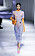 Modell med orange body med hög hals och långa ärmar som går över i handskar. Över bodyn har modellen en ljuslila transparent klänning i figurnära modell. Klänningen är kortärmad och vadlång och har mönster i olika stilar. Look från Fendi ss21.