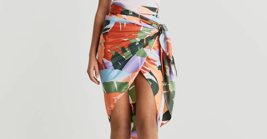 Sarong, Gina tricot. Modell med mönstrad sarong om höften. Palmbladsmönster i ljuslila, ljusblått, orange, rött och ljusgrönt och mörkgrön. Sarong från Gina tricot.