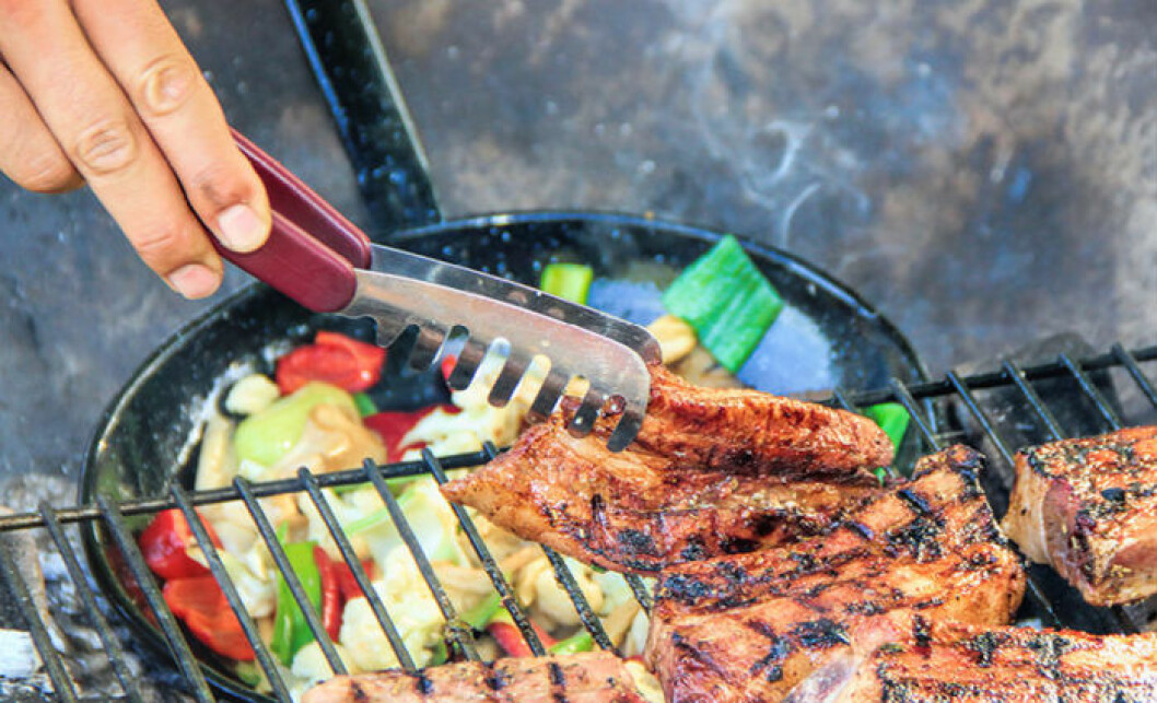 person som vänder kött på grillen