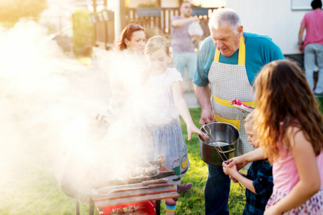 Se till att du grillar säkert hemma i trädgården. Bild: Shutterstock/IBL Äldre man grillar med sina barnbarn. Det röker väldigt mycket från grillen.