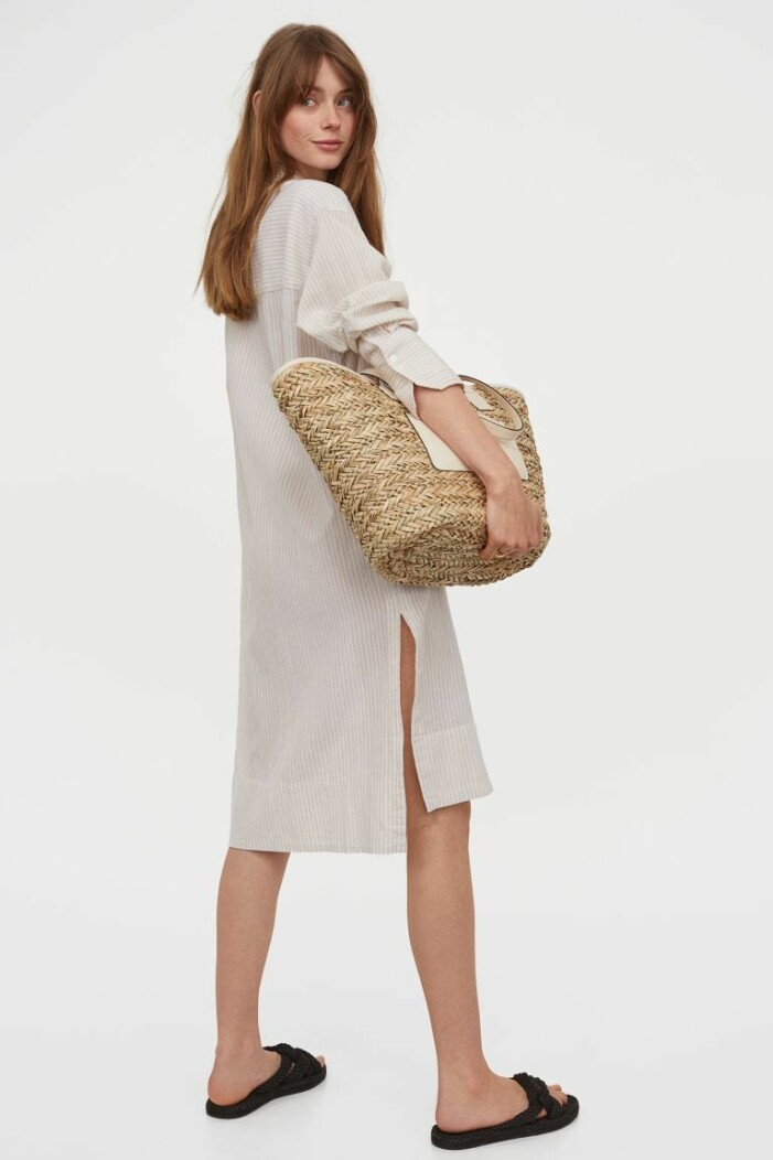 Skjortklänning, H&M. <a target="_blank" rel="nofollow" href="https://track.adtraction.com/t/t?a=1268004454&as=1218462148&t=2&tk=1&epi=an-skjortklanning&url=https://www2.hm.com/sv_se/productpage.0988614001.html">Klicka på länken för att komma direkt till produkten!</a> Skjortklänning i lång modell i vit och beigerandigt. Skjortklänningen är plåtad på en modell och stylad med stråväska och platta sandaler. Outfit från H&M.