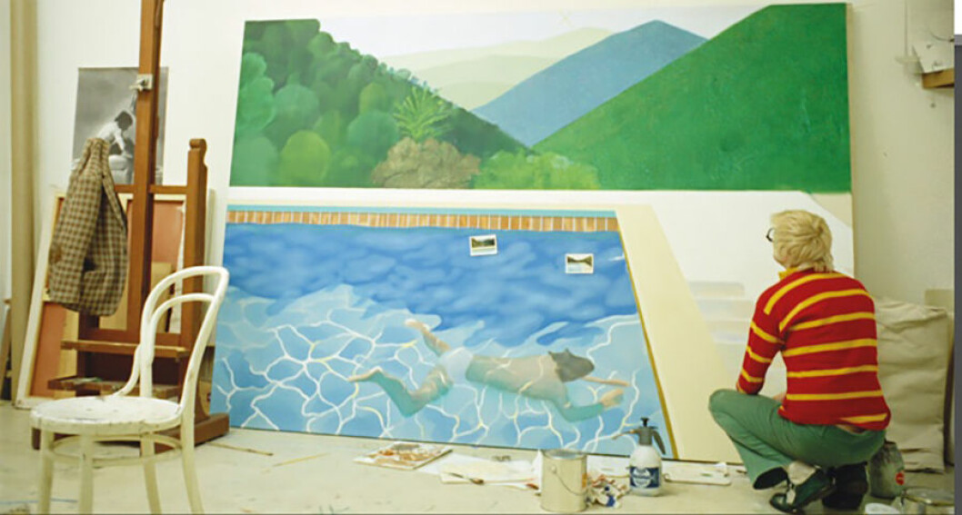 David Hockney i sin ateljé med en halvfärdig ”Portrait of an Artist”, från dokumentären ”A Bigger Splash” (1974). Foto: Jack Hazan / Buzzy Enterprises Ltd David Hockney i sin ateljé