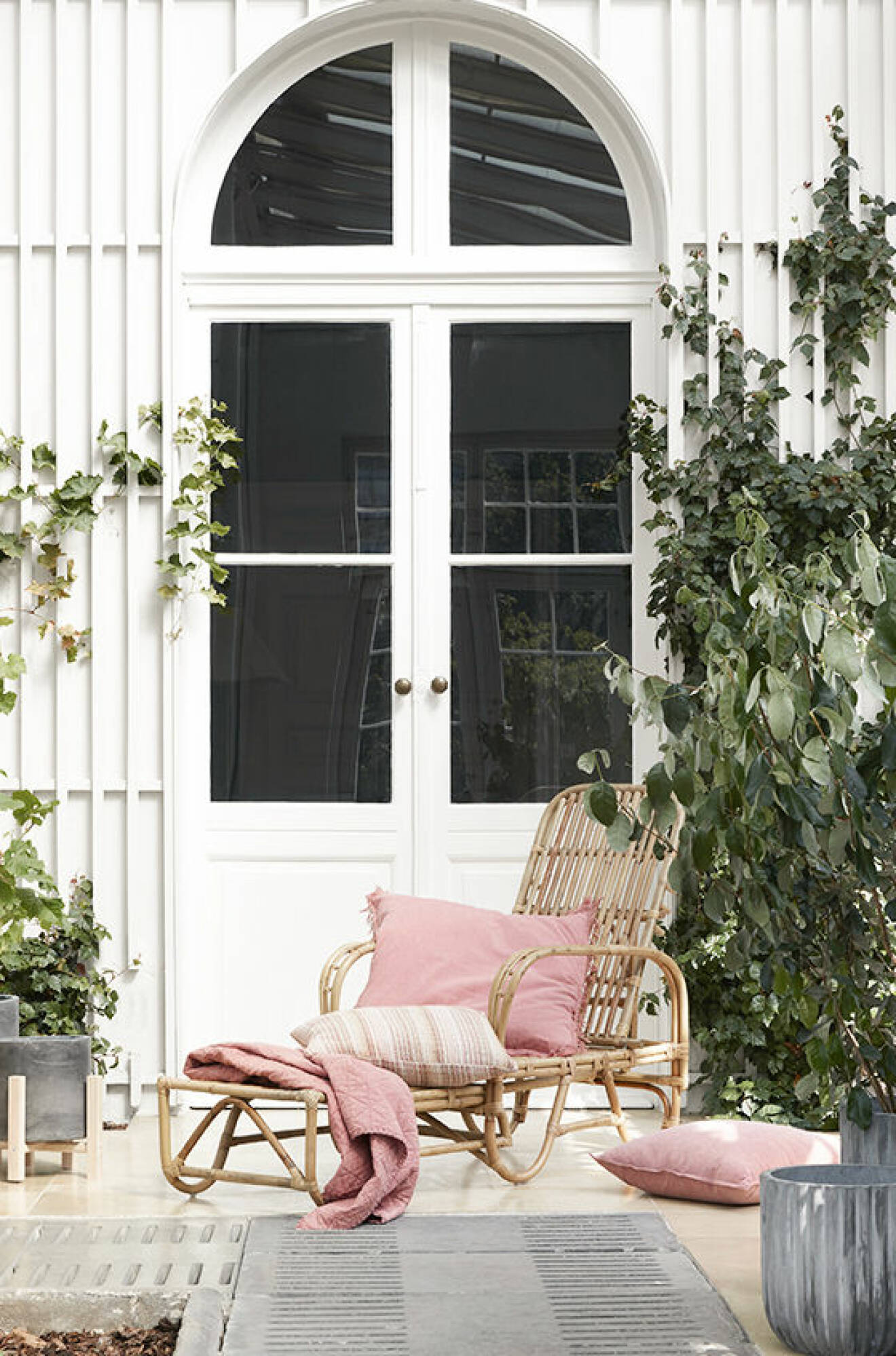 Rattan chair with pink pillows and a throw. 