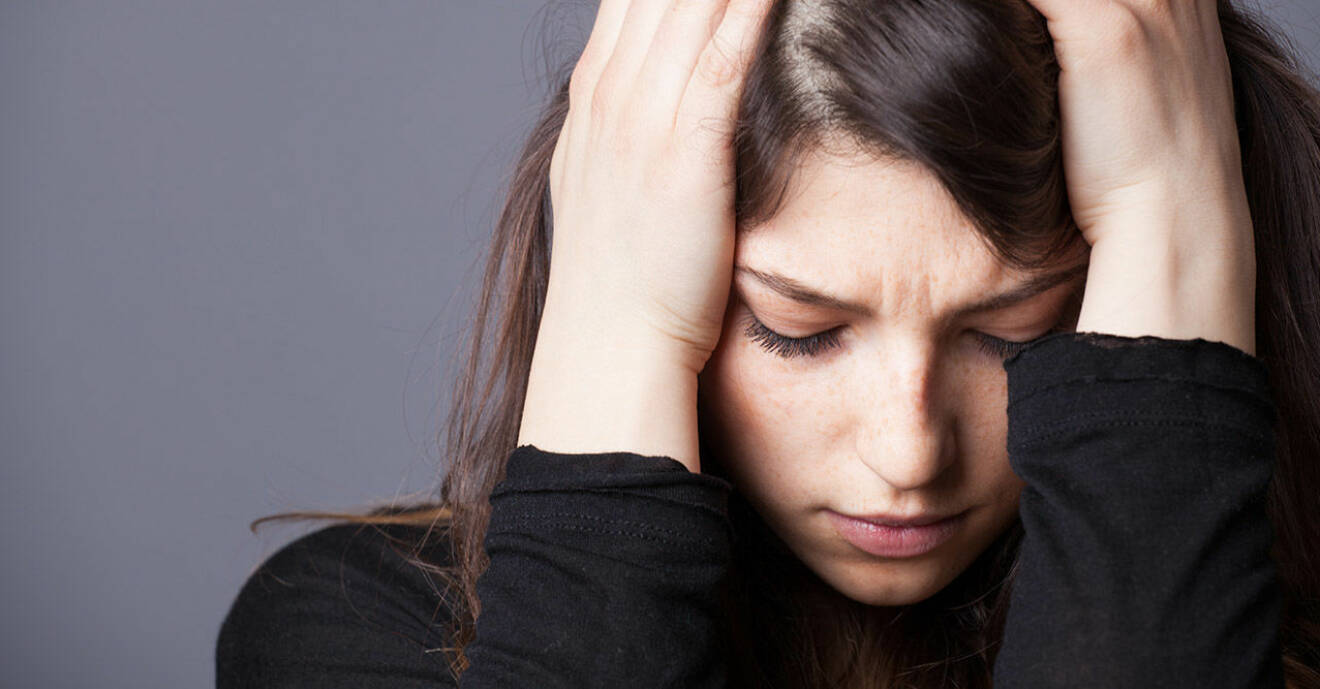 Kvinna med huvudet i händerna mår dåligt och lider av ångest
