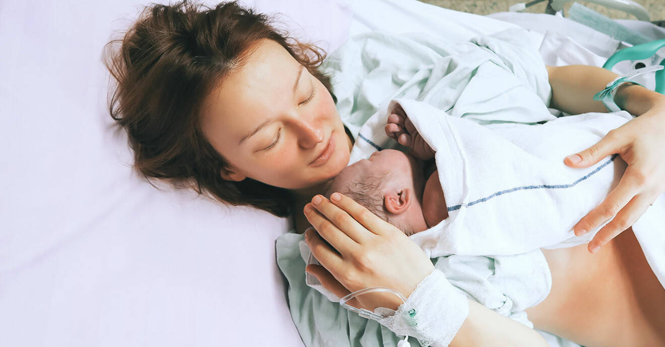 Kvinna håller sitt nyfödda barn i famnen efter förlossning