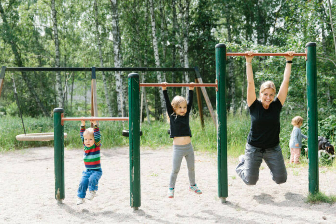 En mamma som tränar i en lekpark tillsammans med sina två barn.