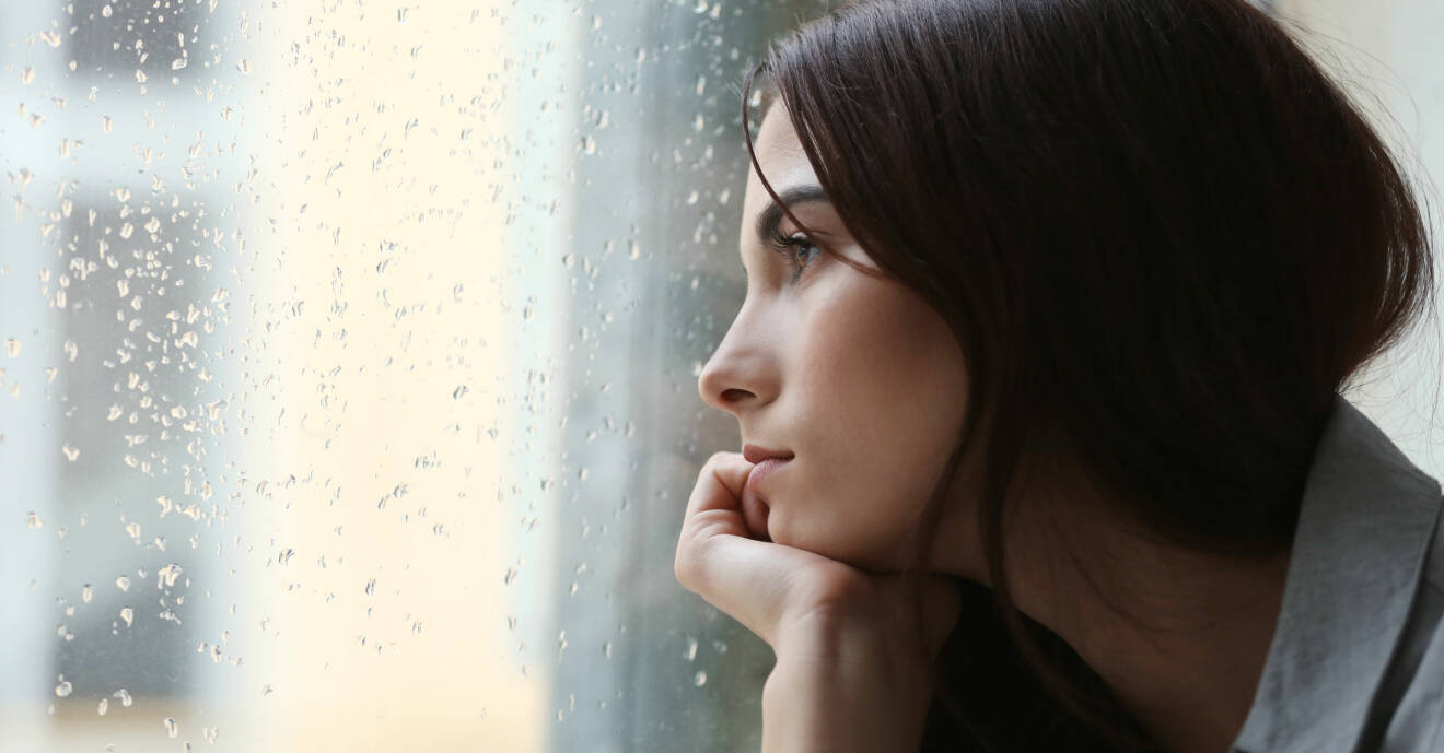 Kvinna tittar ut på regn genom fönster