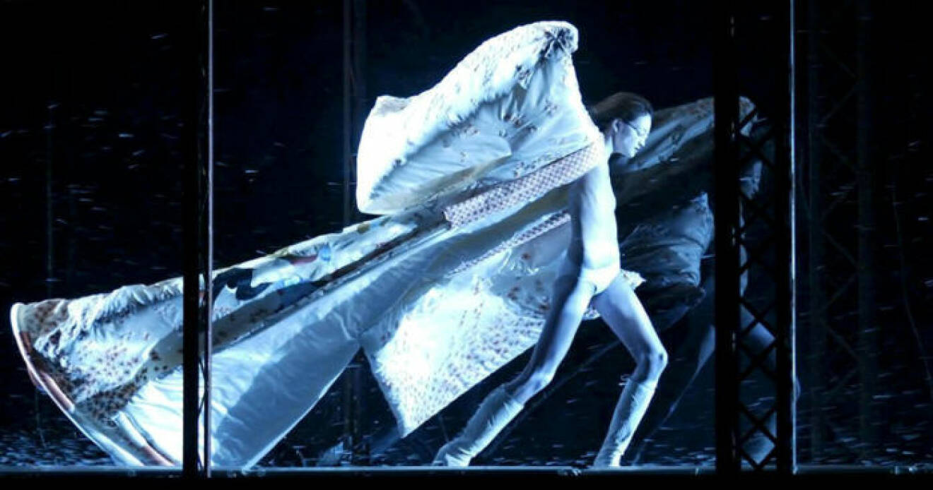 En modell står i en vindtunnel med en lång cape fladdrande bakom sig.