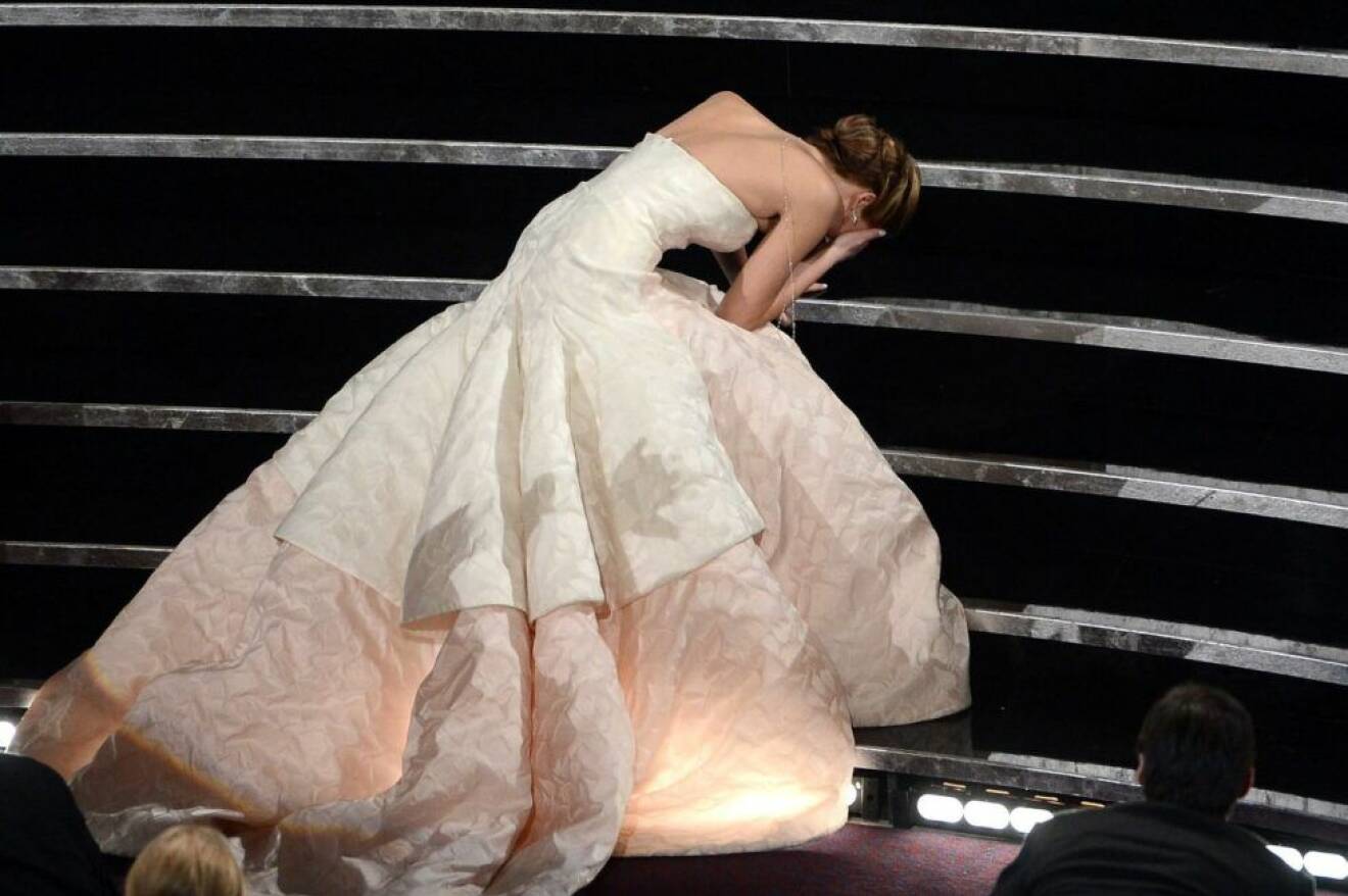 Jennifer Lawrence ligger i en trapp med en stor vit klänning
