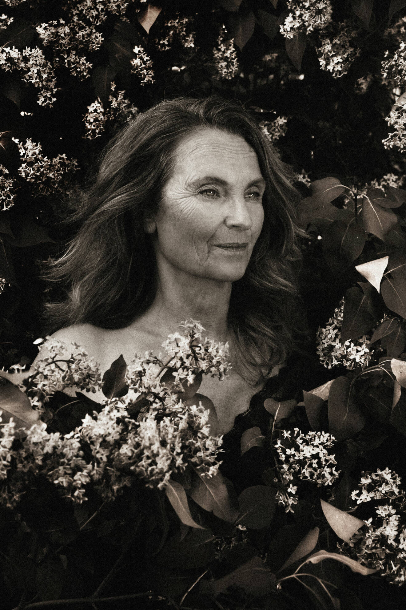 Suzanne Reuter svartvit bland blommor, avklädd