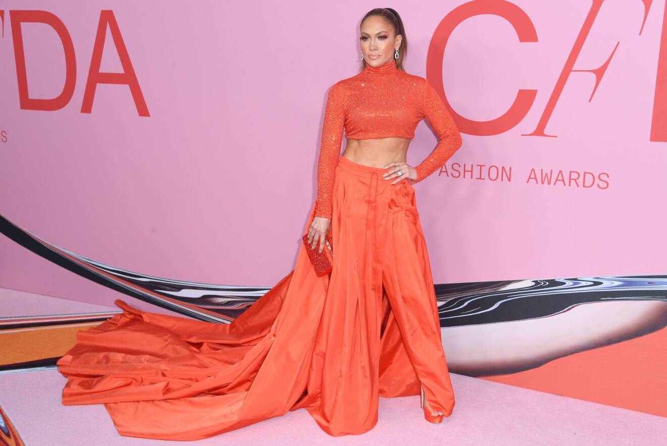 Jennifer Lopez i orange byxor med släp och en orange långärmad magtröja