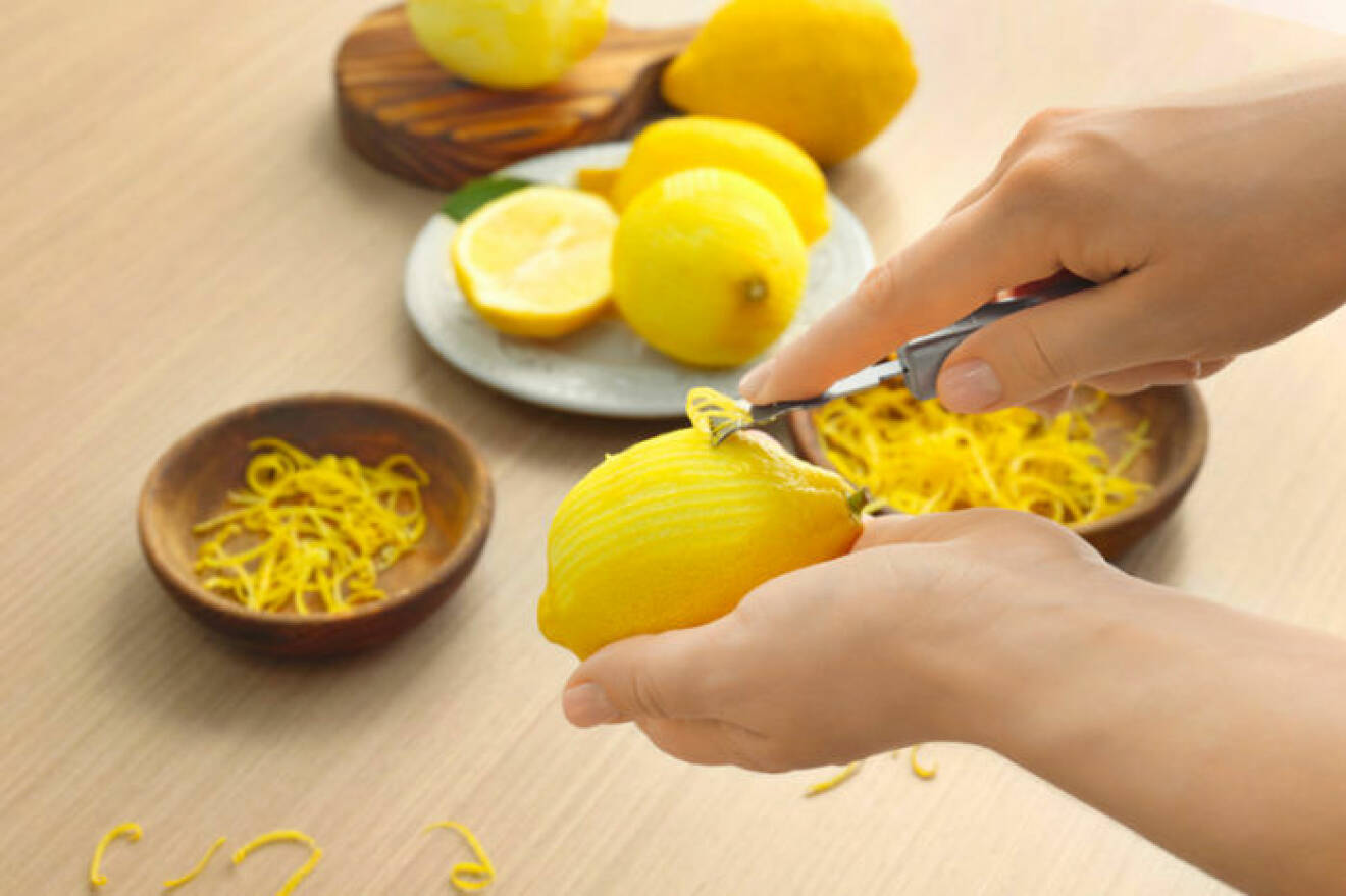 Tar zest från citron med hjälp av zestjärn.