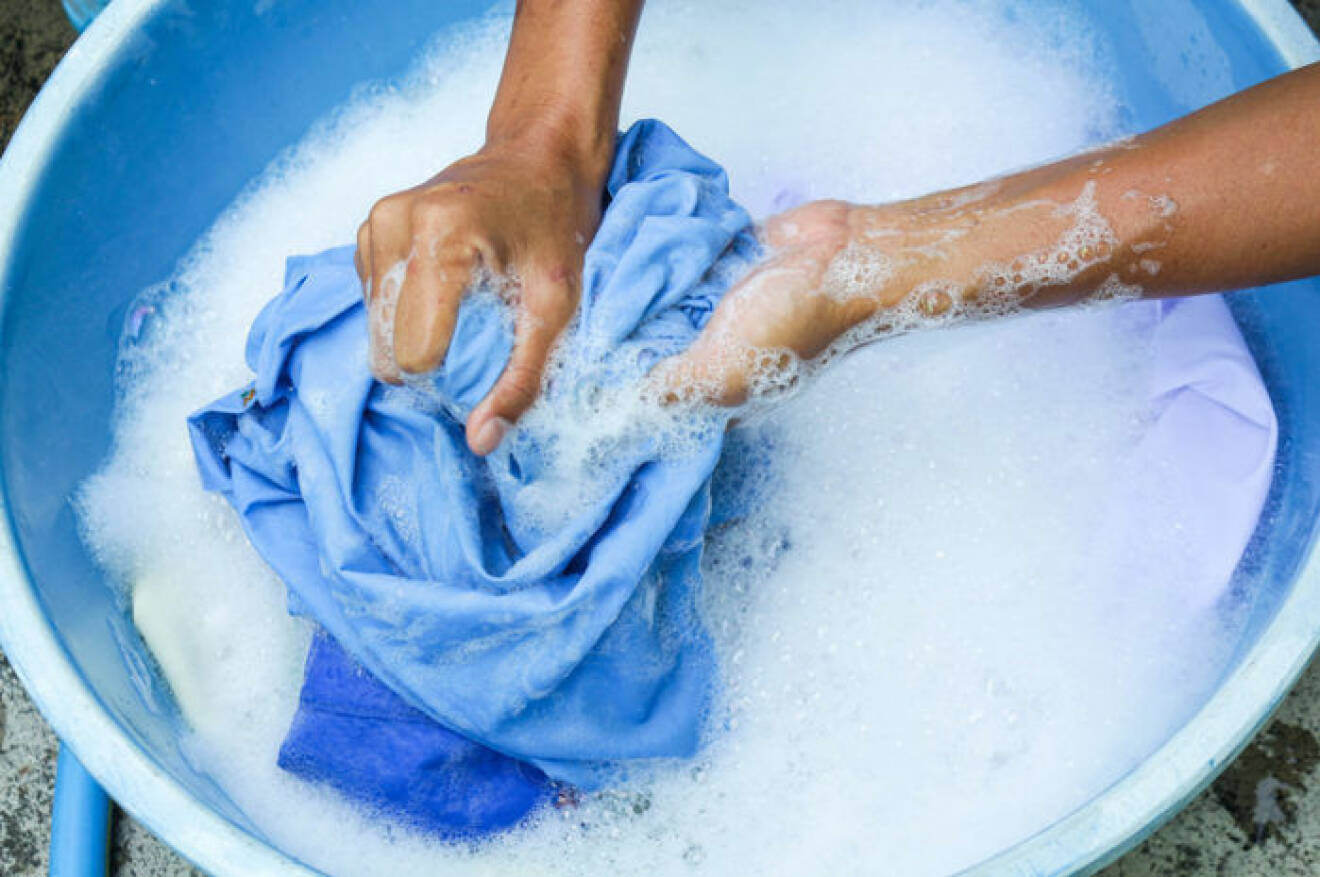 Blått plagg handtvättas i en blå balja.