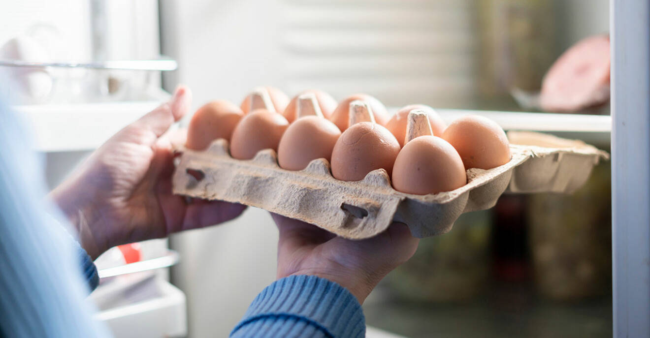 Kvinna ställer in ägg i kartong i kylskåpet