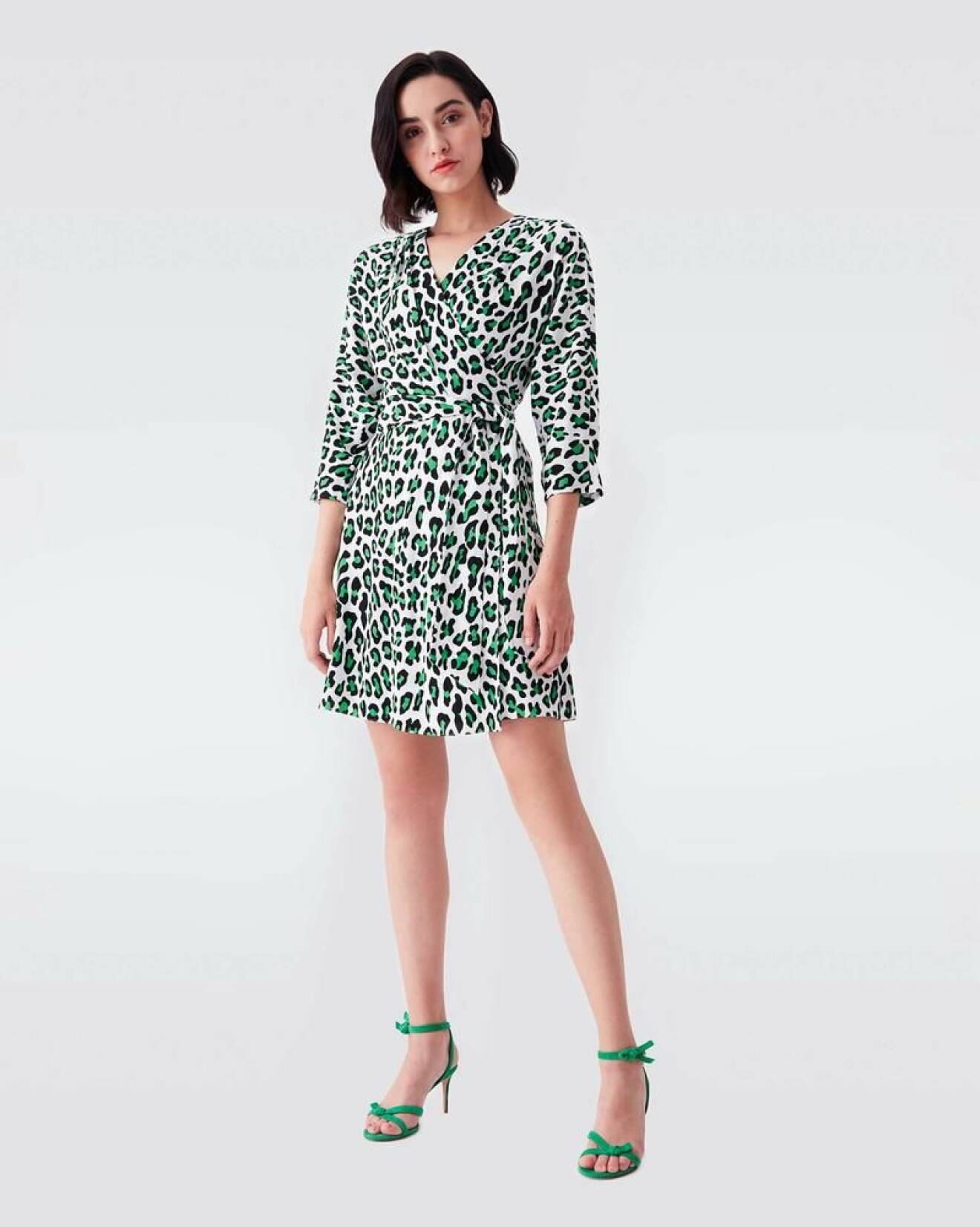Wrap-klänning i kort modell. Leopardprint med grönt och svart på vit bakgrund.