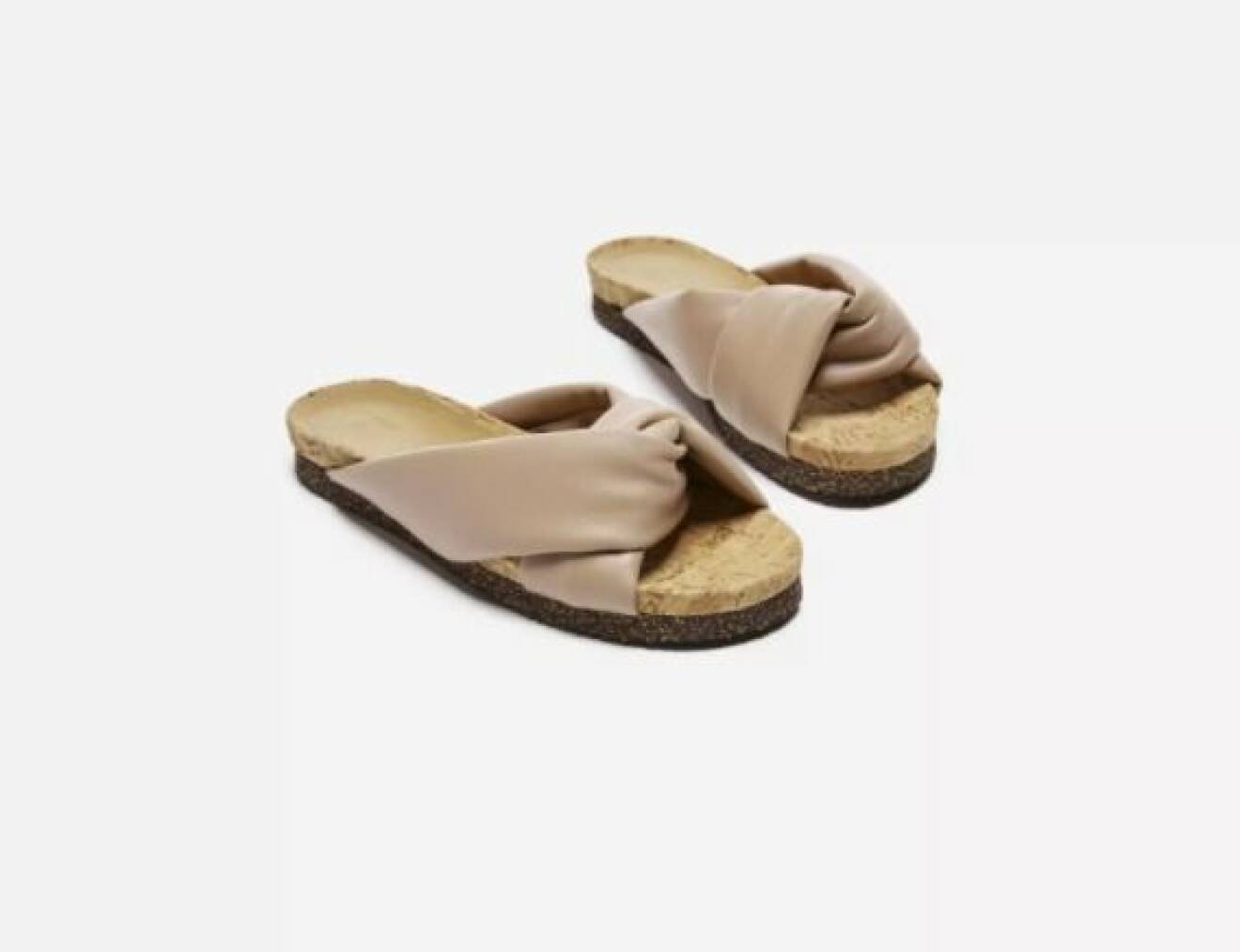 Platta sandaler i beige veganskinn, bred, tvinnad rem över tån.