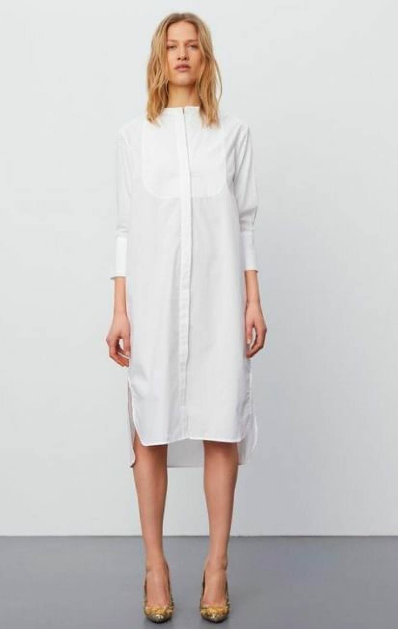Modell med en vit skjortklänning utan krage. Långa ärmar och klänningen slutar en bit under knät. Skjortklänning från Day Birger et Mikkelsen.