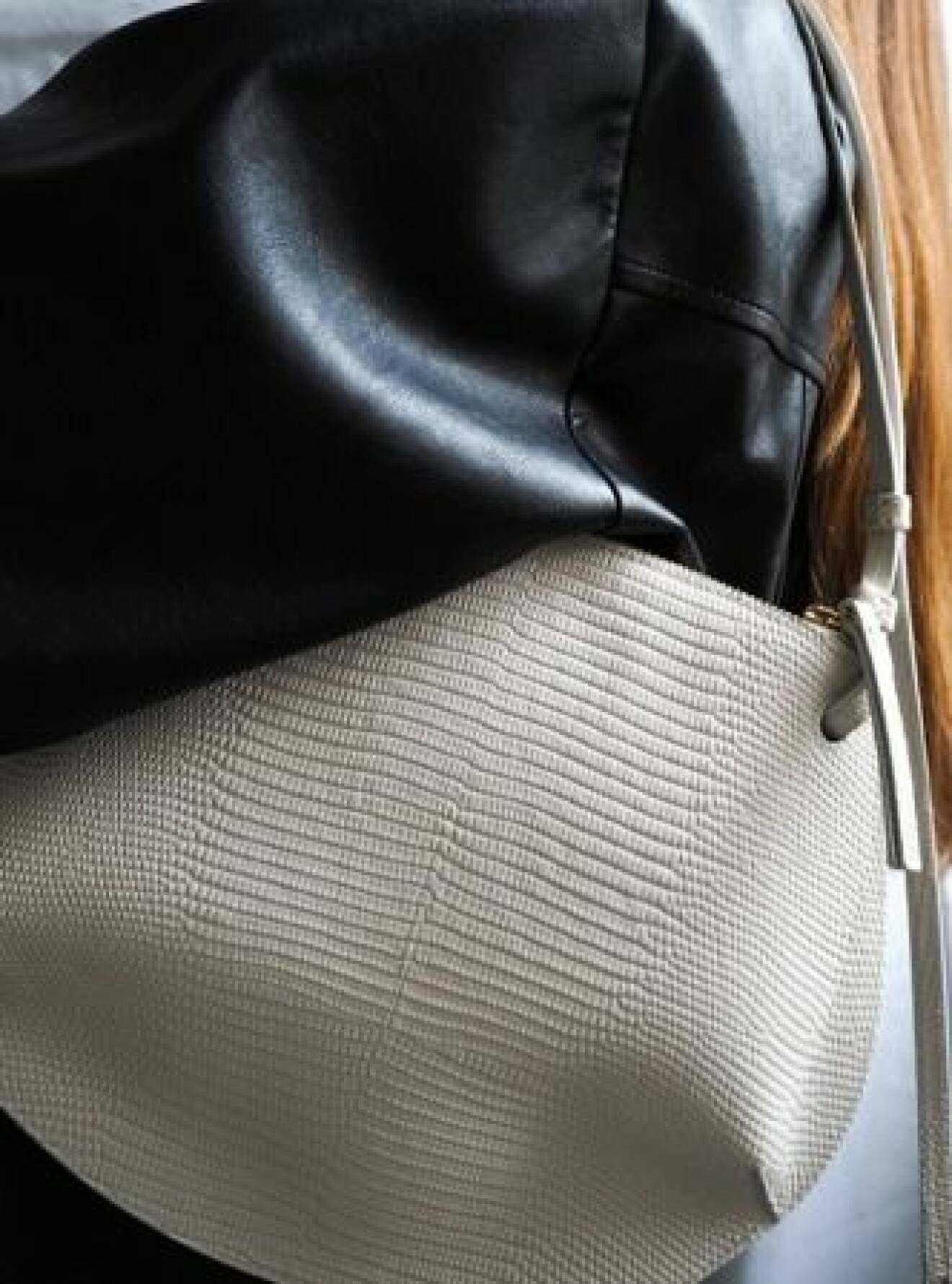 Närbild på liten, vit handväska i skinn med struktur. Väska från Little liffner.