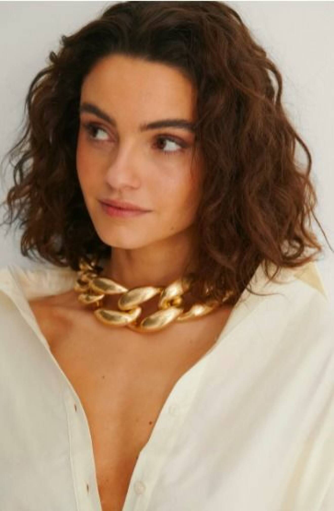 Modell med bred, guldfärgad halskedja på sig. Halsband från Nakd.