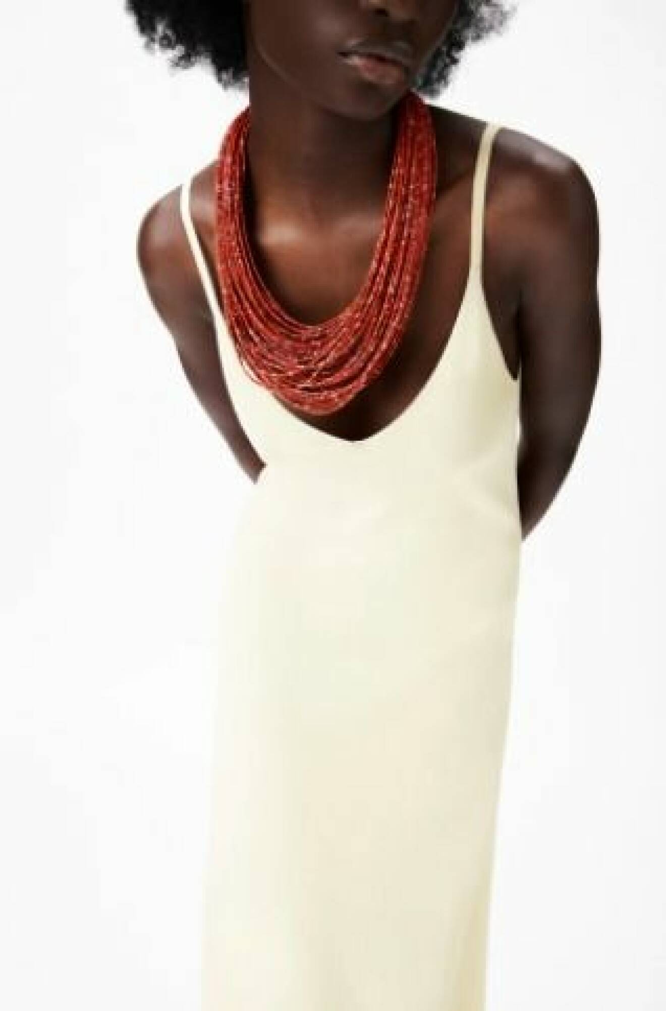 Modell med ett stort halsband med multirader av röda små pärlor. Halsband från Zara.
