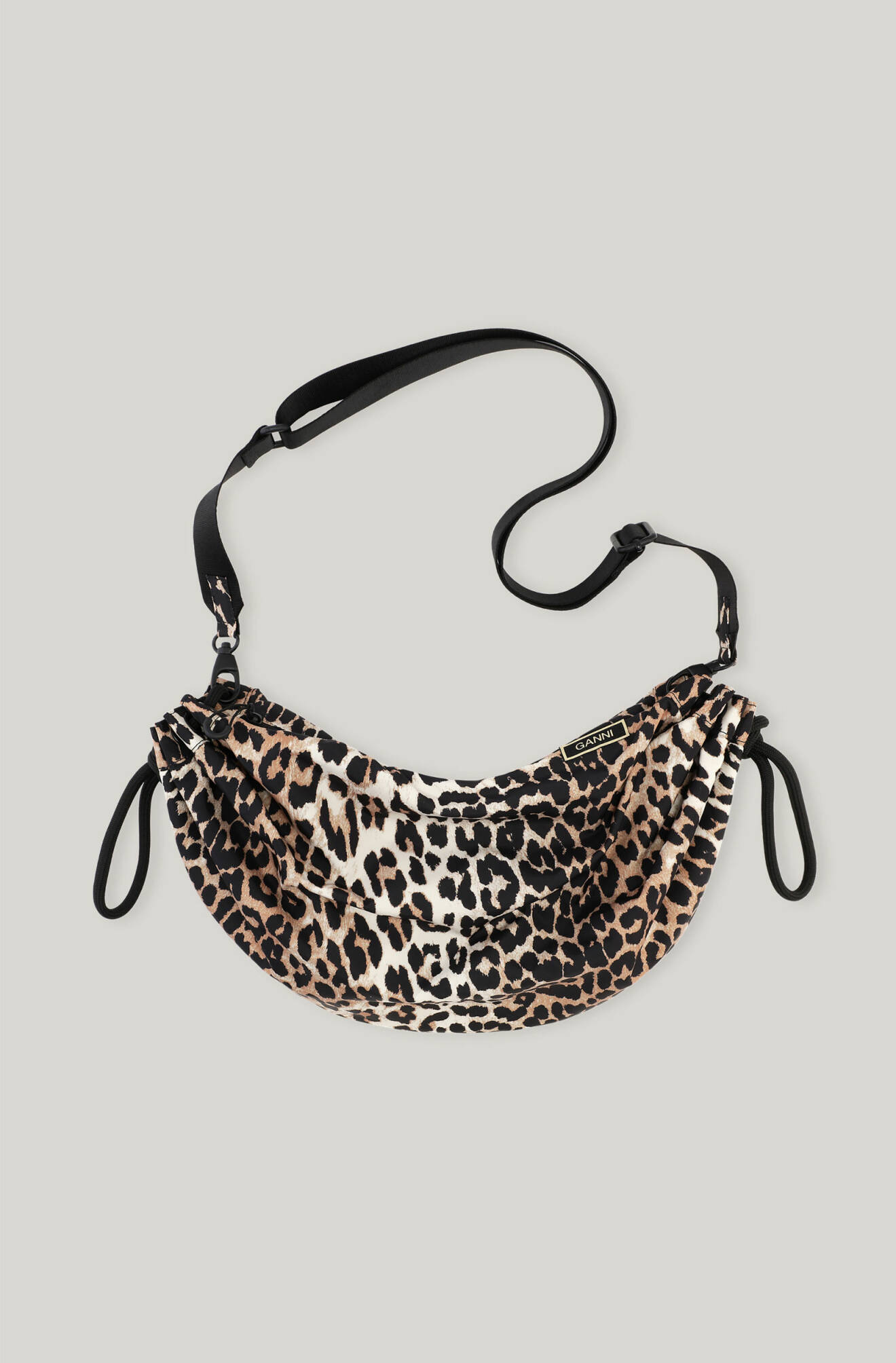Leopardmönstrad väska formad som en båge med avtagbar, svart axelrem. Väska från Ganni.
