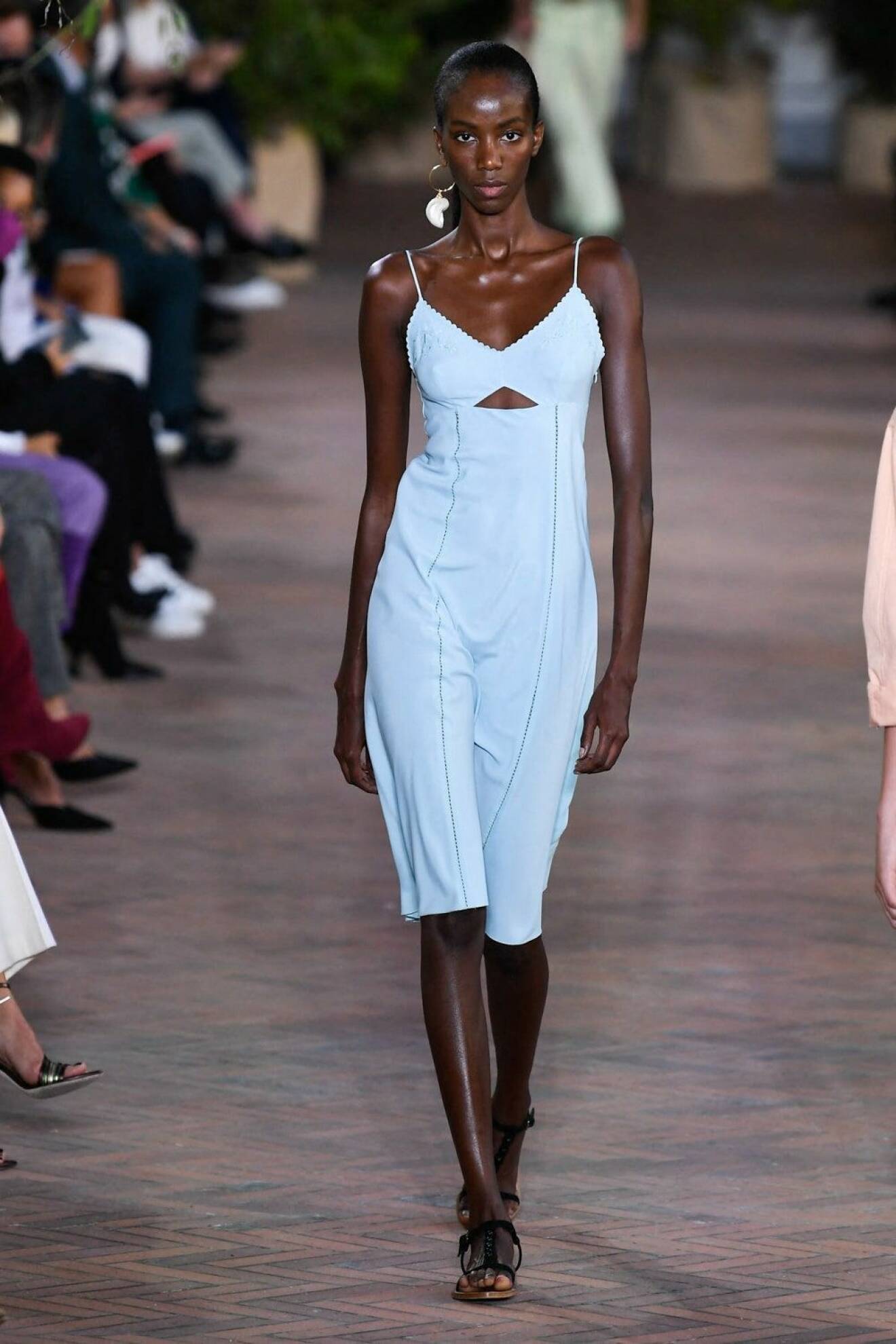 Modell med ljusblå, midiklänning i minimalistisk design. Klänningen har en trekantig cut out-detalj under bystet. Look Alberta Ferretti.