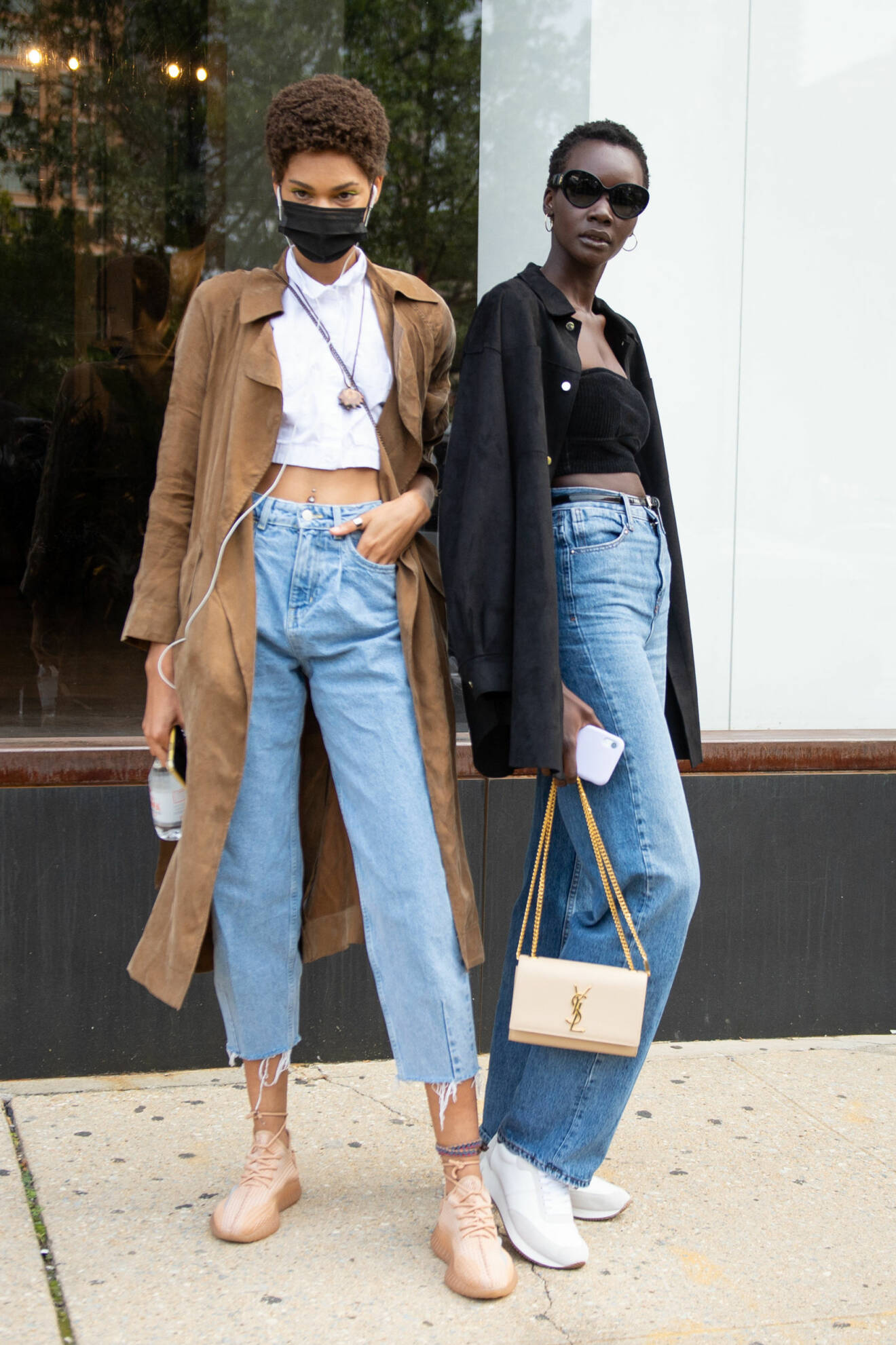 Två tjejer fotograferade på stan. Båda har jeans i blå nyans. Den ena har raka, långa och den andra croppade. Till det plagg i svart, brunt och vitt. Street style-bild.
