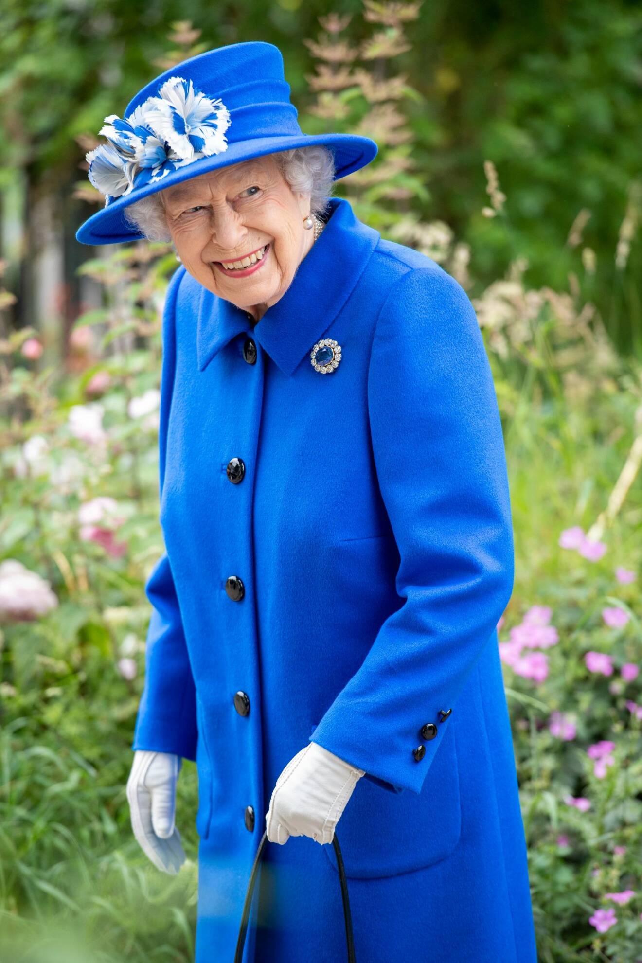 Drottning Elizabeth i klarblå dräkt med rock hatt med blåvita fjädrar i.