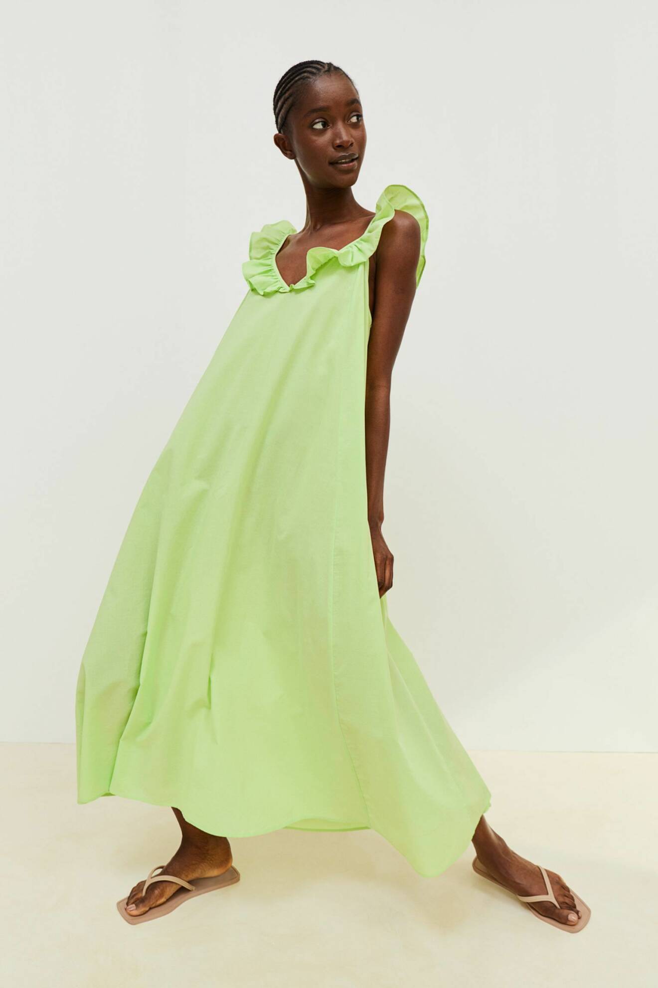 Modell med limegrön sommarklänning i midimodell med volangdetalj som axelband. Vid klänning från H&amp;M.