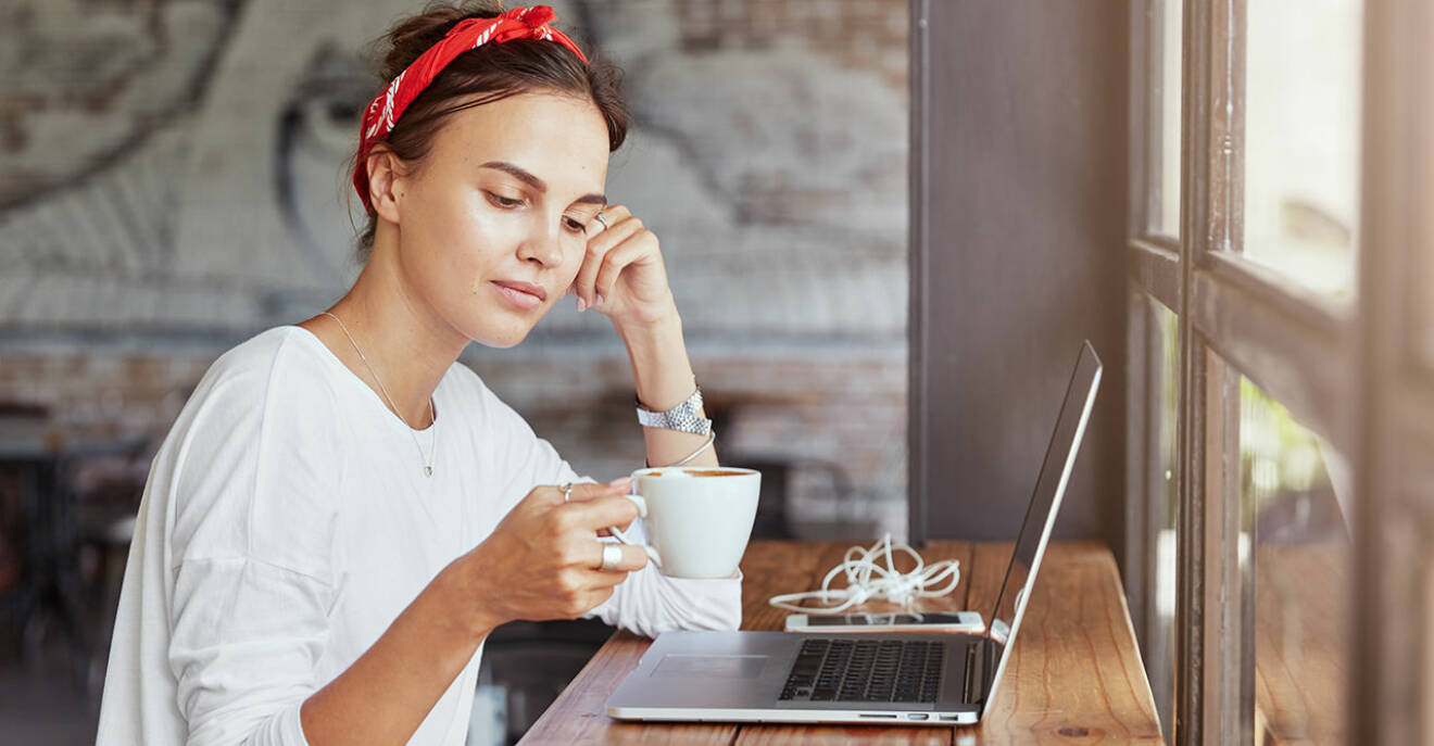 Kvinna sitter vid sin dator med en kaffekopp