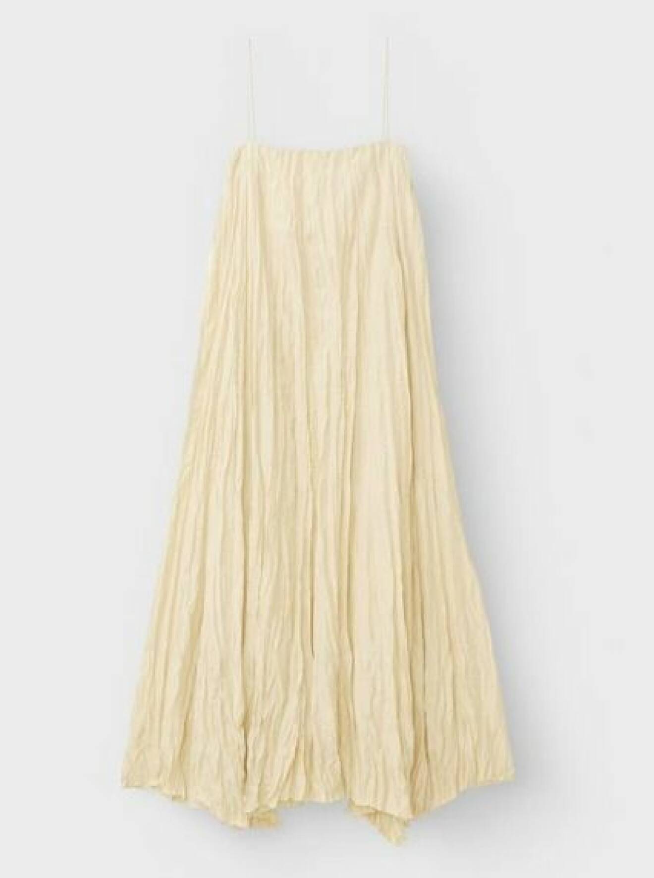 Champangefärgad klänning i crinklat, skrynkligt material. Klänningen går ner till anklarna och är i vid modell med tunna spagettisband upptill och rak skärning vid bystet. Klänning från Toteme.