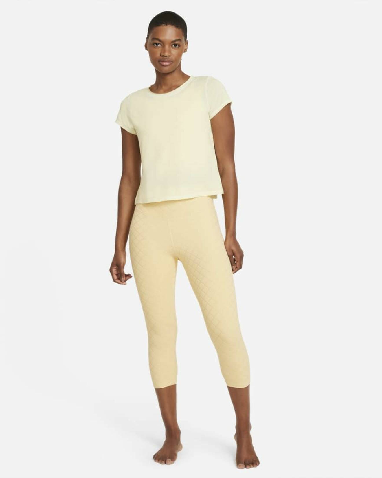 Modell med ljusgul tränings t-shirt och gula trekvarts tights. Träningskläder från Nike.